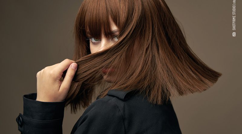 Modische Frau, die ihr Gesicht elegant mit ihren Haaren verdeckt