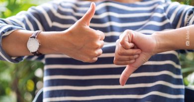 Eine Frau zeigt mit einer Hand einmal Daumen nach oben und mit der anderen einmal Daumen nach unten