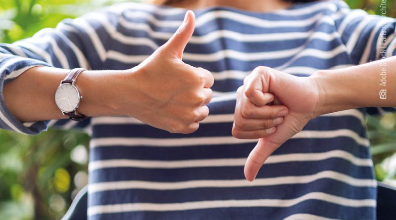 Eine Frau zeigt mit einer Hand einmal Daumen nach oben und mit der anderen einmal Daumen nach unten